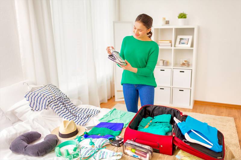 Abbigliamento Egiziano, una ragazza con maglione verde prepara la valigia Abbigliamento Egiziano, una ragazza con maglione verde prepara la valigia