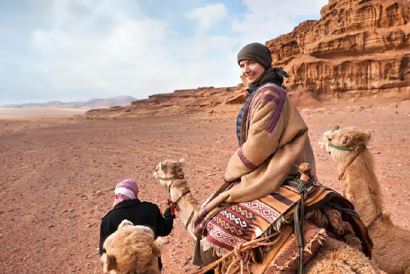 una ragazza cavalca un cammello a Wadi Rum, Cosa vedere in giordania una ragazza cavalca un cammello a Wadi Rum, Cosa vedere in giordania