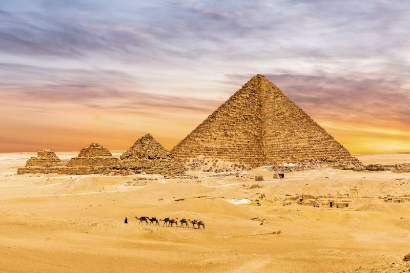 la piramide di cheope accanto a altre tre piccole piramidi sotto il cielo azzurro