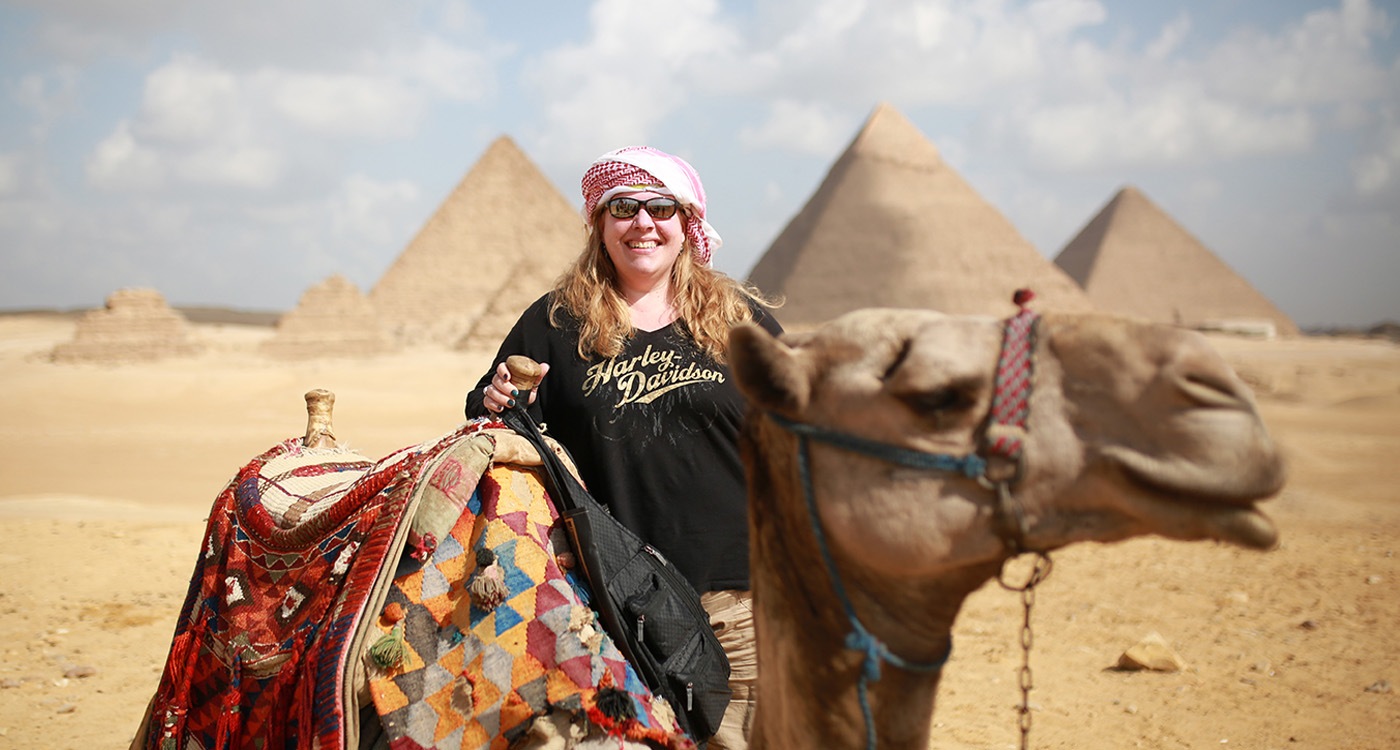 Una donna con un cammello davanti alle piramidi